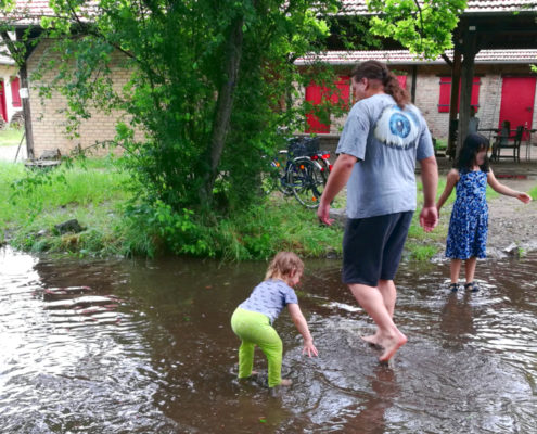 Daniel und zwei Kinder in einem aus Regenwasser entstandenen Planschbecken